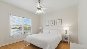 A bedroom with a large bed, two bedside tables, a ceiling fan, and a window with blinds. - Kool Breeze by AvantStay | Boat Ramp + Hot Tub (Denver)