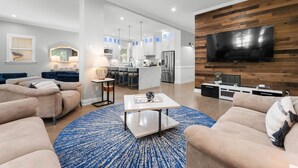 A modern living room with a large TV, beige sofas, a coffee table, and a blue rug. - Laid Back Lake Life by AvantStay | Waterfront View (Mooresville)
