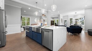 A modern kitchen with a central island, stainless steel appliances, and pendant lighting. - Laid Back Lake Life by AvantStay | Waterfront View (Mooresville)