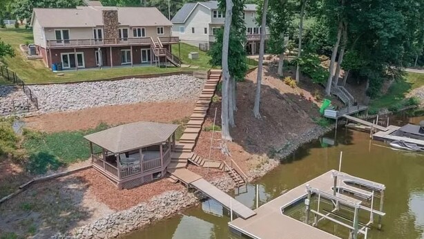 A lakeside property with a wooden dock, a covered seating area, and a large house with multiple levels and a deck. - Shades of Summer by AvantStay | Gazebo, Dock, View (Denver)