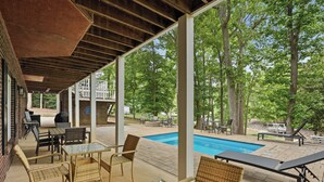 Une terrasse extérieure avec une piscine, des meubles en osier et un espace abrité équipé d’un barbecue.
