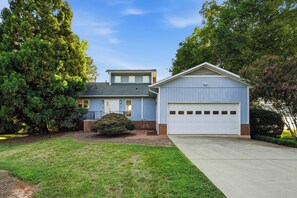 A two-story house with a garage, surrounded by trees and a well-maintained lawn.