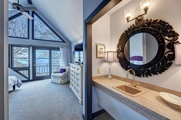 A bedroom with a large window, a ceiling fan, and a dresser.