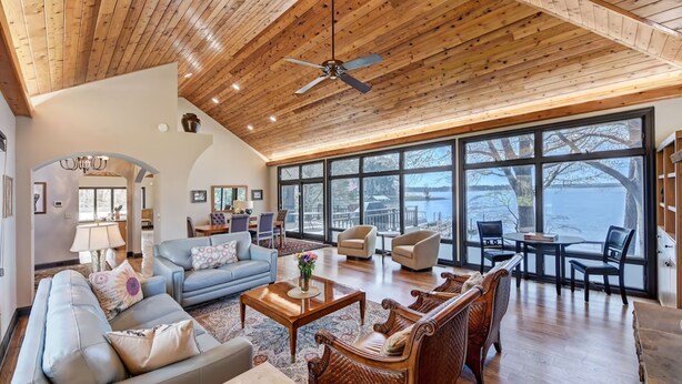 A spacious living room with a high ceiling, large windows, and a view of the outdoors. - Landover Lodge by AvantStay | Waterfront + Dock (Mooresville)