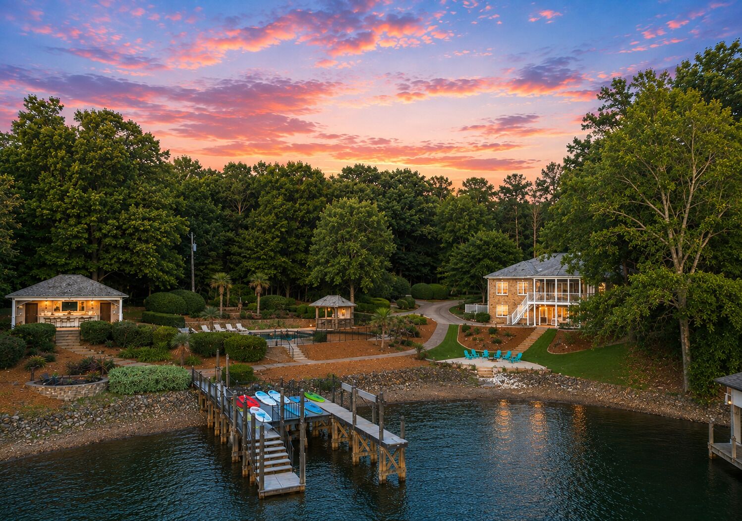 A lakeside property with a dock, a pool, and a house with a large deck.