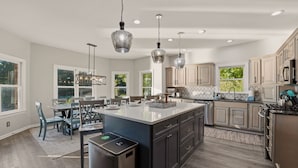 A spacious kitchen with a central island, pendant lighting, and a view of the outdoors. - Lakefront Estate | Pool + Hot Tub + Dock + Sauna | Oasis at Ballycastle (Mooresville)