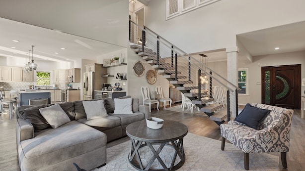 A spacious living area with a modern staircase, a sofa set, and a dining area. - Lakefront Estate | Pool + Hot Tub + Dock + Sauna | Oasis at Ballycastle (Mooresville)