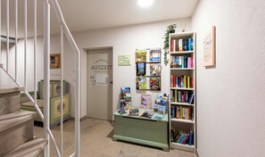 Ein Wellnessbereich mit Sauna und Fitnessraum, eine Treppe sowie ein Bücherregal mit verschiedenen Büchern.