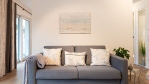 Una sala moderna con un sofá gris, un cuadro abstracto grande y una planta en maceta.