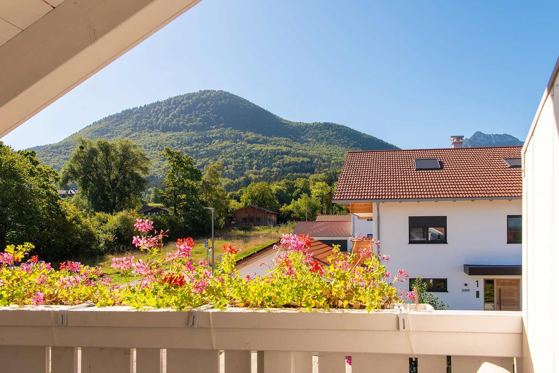 Une vue sur une montagne, avec un bâtiment blanc et un toit recouvert de tuiles rouges.