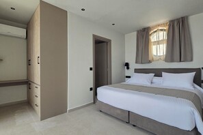 Een hotelkamer met een bed, een kledingkast, een deur en een raam met gordijnen.