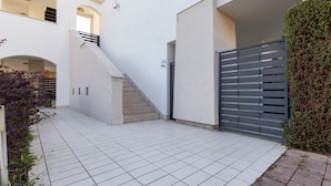 Een modern gebouw met een betegelde binnenplaats, een trap en een hekwerk.