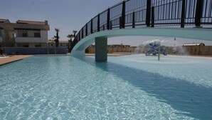 Ein Schwimmbecken mit Brücke, klarem Wasser und einer Wasserspielen-Anlage.