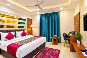 A hotel room with a bed, a desk, a chair, a TV, and a ceiling fan. - Hotel All Time Residency - Near Connaught Place New Delhi (New Delhi)