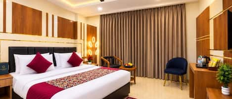 A hotel room with a large bed, a desk, a chair, a ceiling fan, and a large window with curtains.