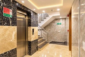 A modern elevator with a digital display, a staircase with a handrail, and a sign indicating the use of stairs in case of fire. - Hotel All Time Residency - Near Connaught Place New Delhi (New Delhi)
