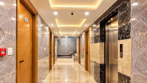 A hotel corridor with marble flooring, wooden doors, and a marble wall with an elevator. - Hotel All Time Residency - Near Connaught Place New Delhi (New Delhi)