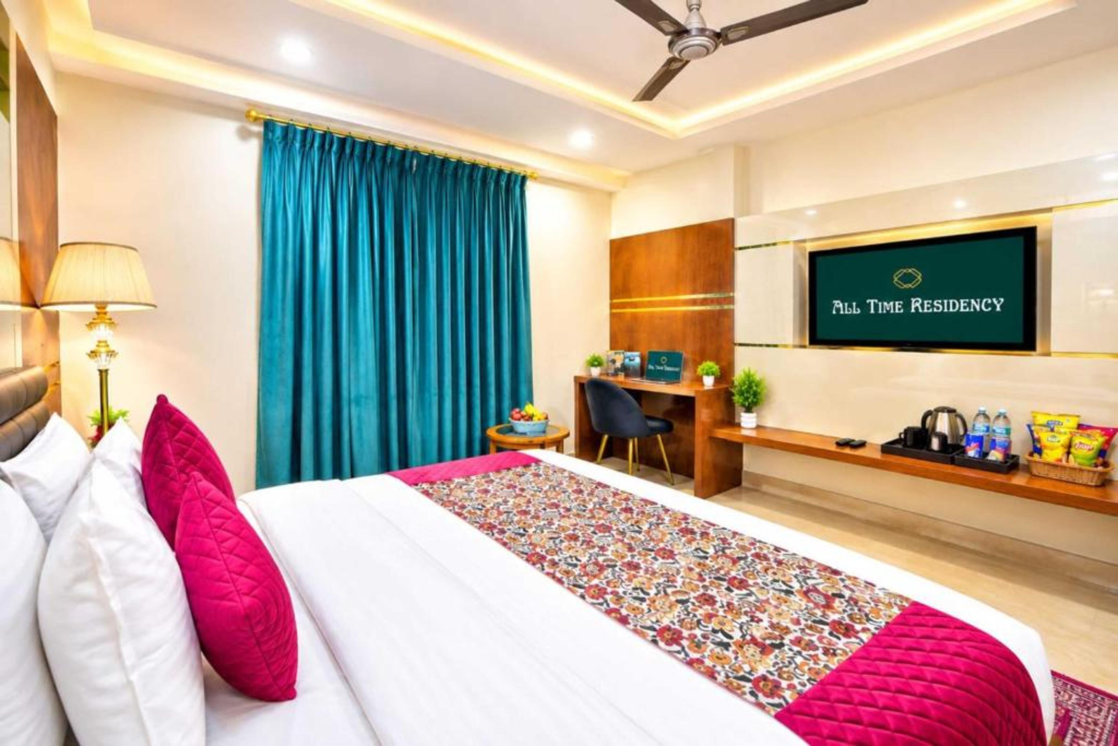 A hotel room with a bed, a desk, a TV, and a ceiling fan.