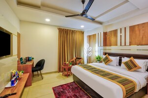 A hotel room with a bed, desk, chair, and a ceiling fan.