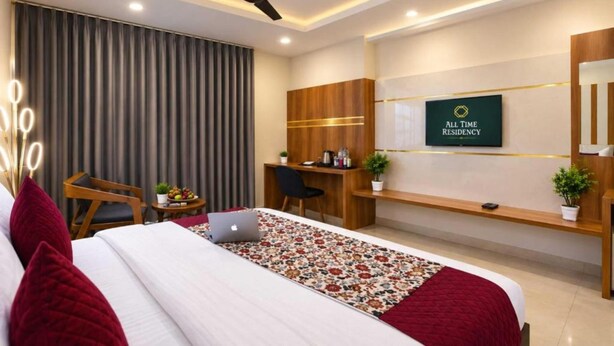 A hotel room with a bed, a desk, a chair, a laptop, a ceiling fan, and a wall-mounted TV. - Hotel All Time Residency - Near Connaught Place New Delhi (New Delhi)