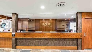 A reception desk at Glacier Lodge with a wooden design and a sign above it.