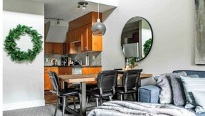 A compact living space with a dining area, kitchen, and a cozy seating area with a sofa and a blanket.