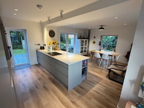 Una cocina moderna con una isla grande, un comedor con mesa y sillas, y vistas al exterior.
