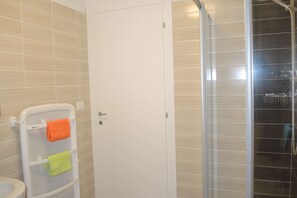 Bathroom features a glass shower enclosure, white toilet, and towel rack.