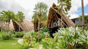 Een resort met gebouwen met rieten daken, een verhard pad en weelderige tropische begroeiing.