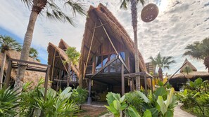 Un edificio con techo de paja y balcón, rodeado de exuberante vegetación tropical.