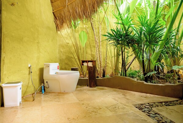 Un baño con inodoro, bidé y un pequeño cubo de basura.