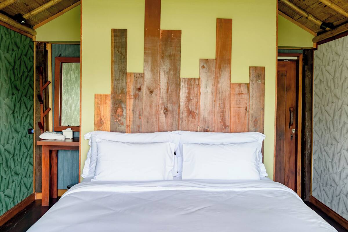 A room with a bed, wooden headboard, and green walls.