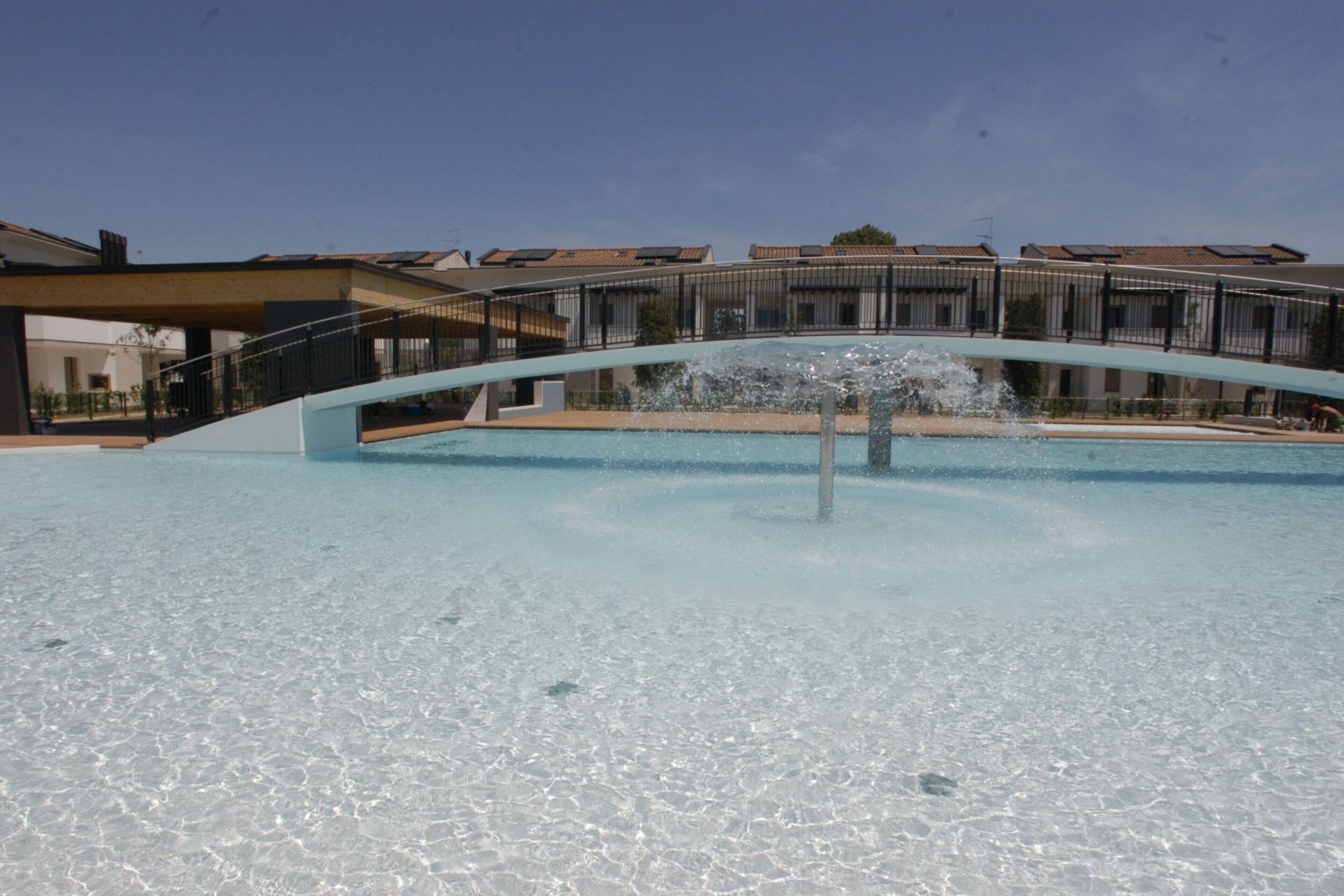 A swimming pool with a fountain, surrounded by buildings with balconies.