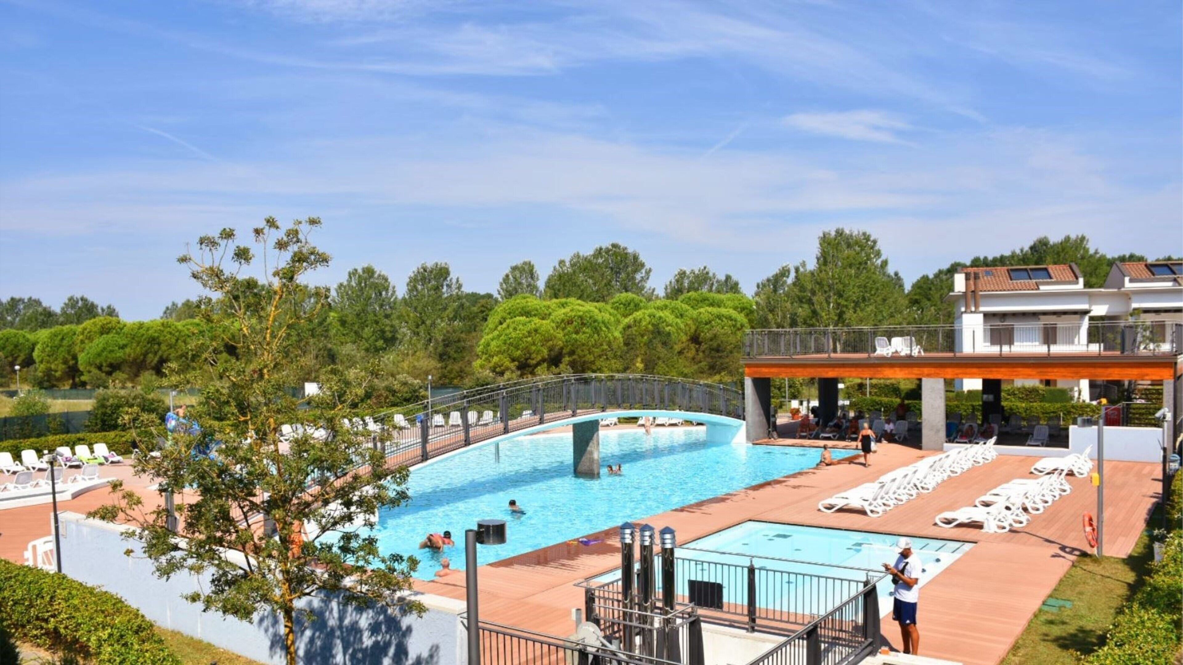 Une piscine avec des chaises longues et une terrasse couverte.