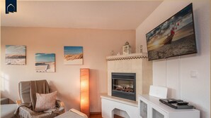 A living room with a fireplace, a television, and artwork on the walls. - Ferienwohnung Strandbrise (Koserow)