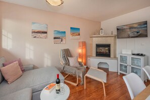 Una sala de estar acogedora con chimenea, un televisor montado arriba y una estantería.