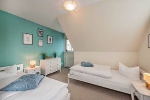 Un dormitorio con dos camas, un aparador, una mesita de noche y decoración en la pared.