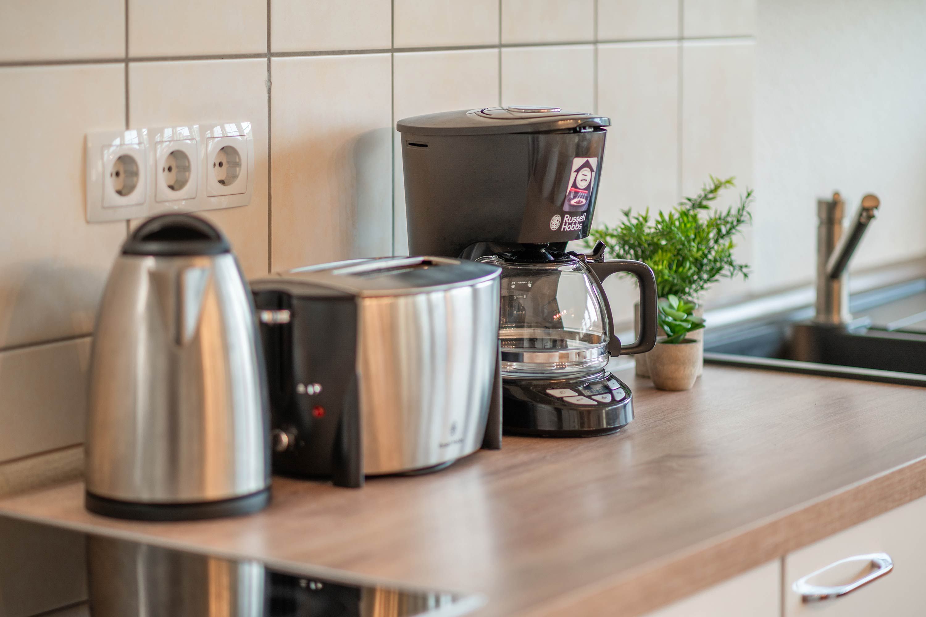 A kitchen counter with a coffee maker, a toaster, and a kettle.