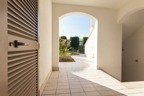 A corridor with a tiled floor leading to an archway.