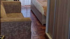 A hotel room with a bed, a chair, and a large window with curtains. - Essence Hotel (Ndenderu)