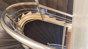 A spiral staircase with black steps and a metal handrail. - Essence Hotel (Ndenderu)