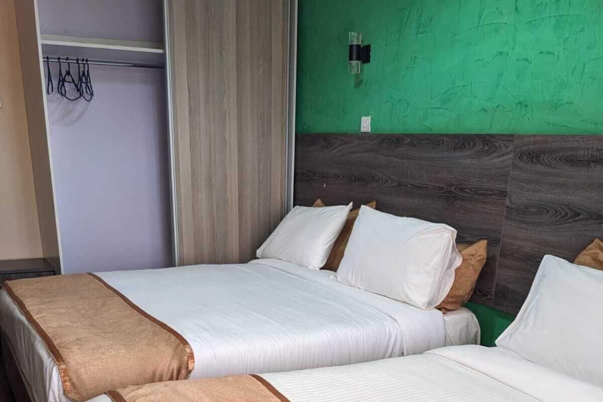 A hotel room with two beds, each with white bedding and a brown accent.
