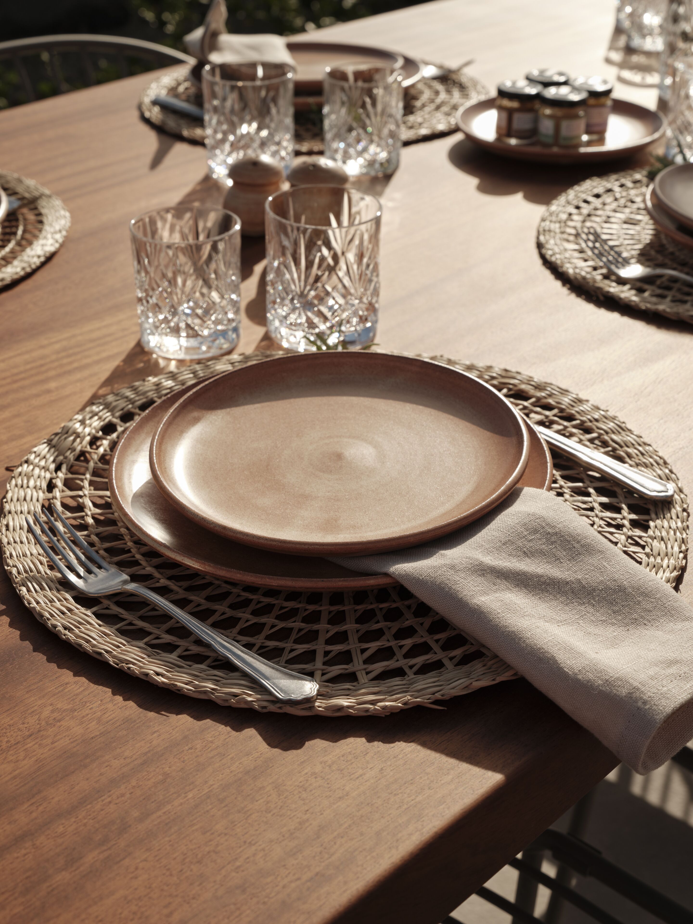 A table set with plates, cutlery, and glassware on a woven placemat.