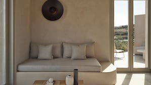 A modern living room with a beige sofa, a round wall decor, and a view of the outdoors through large glass doors.