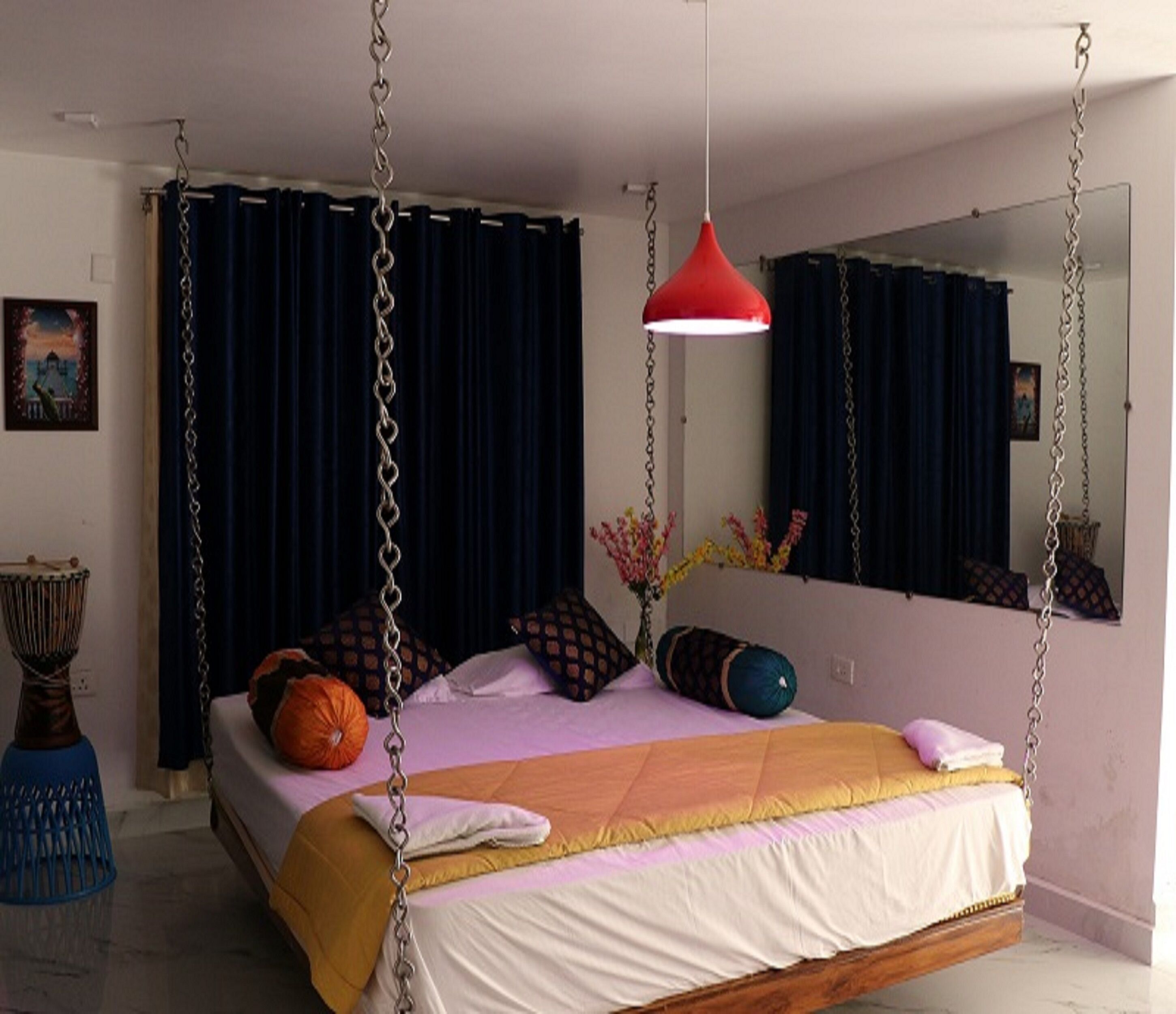 Una cama con una cadena colgante, una lámpara colgante roja y un espejo grande en la pared.