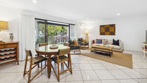 A modern living room with a dining area, a sofa, and a TV. - Lindy Lou's Entire Rental Unit in Sawtell (SAWTELL)