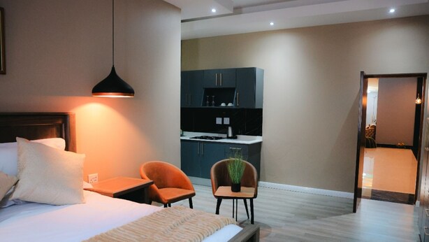 Une chambre d’hôtel moderne équipée d’un lit, d’une table de chevet et d’un petit coin salon avec deux fauteuils.