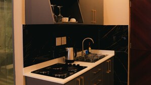 Une cuisine de taille réduite, dotée de meubles de rangement sombres, d’une cuisinière à gaz et d’un seul évier.