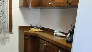 A small kitchen with wooden cabinets, a countertop, and a refrigerator. - Villa sul Mare (Sorso)