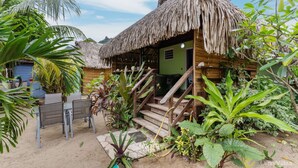 A wooden structure with a thatched roof, surrounded by tropical plants. - Fare Oaoa · on the Haapiti surf pass, sleeps 4 (Moorea)